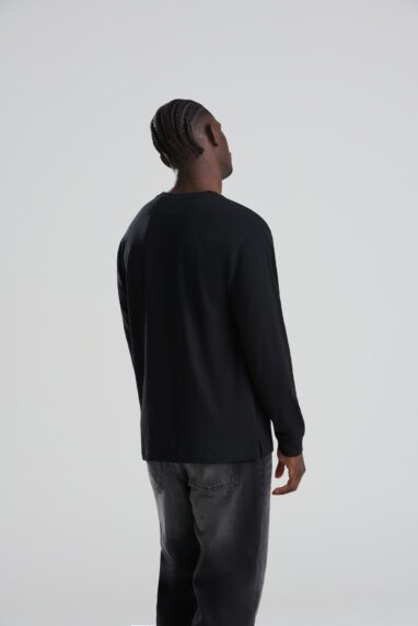 AT012_DEEP_BLACK_DEC2025-DEC2027_053-382x572 - Topline Workwear Man with braided hair wearing a black long-sleeve shirt and dark jeans, viewed from behind.